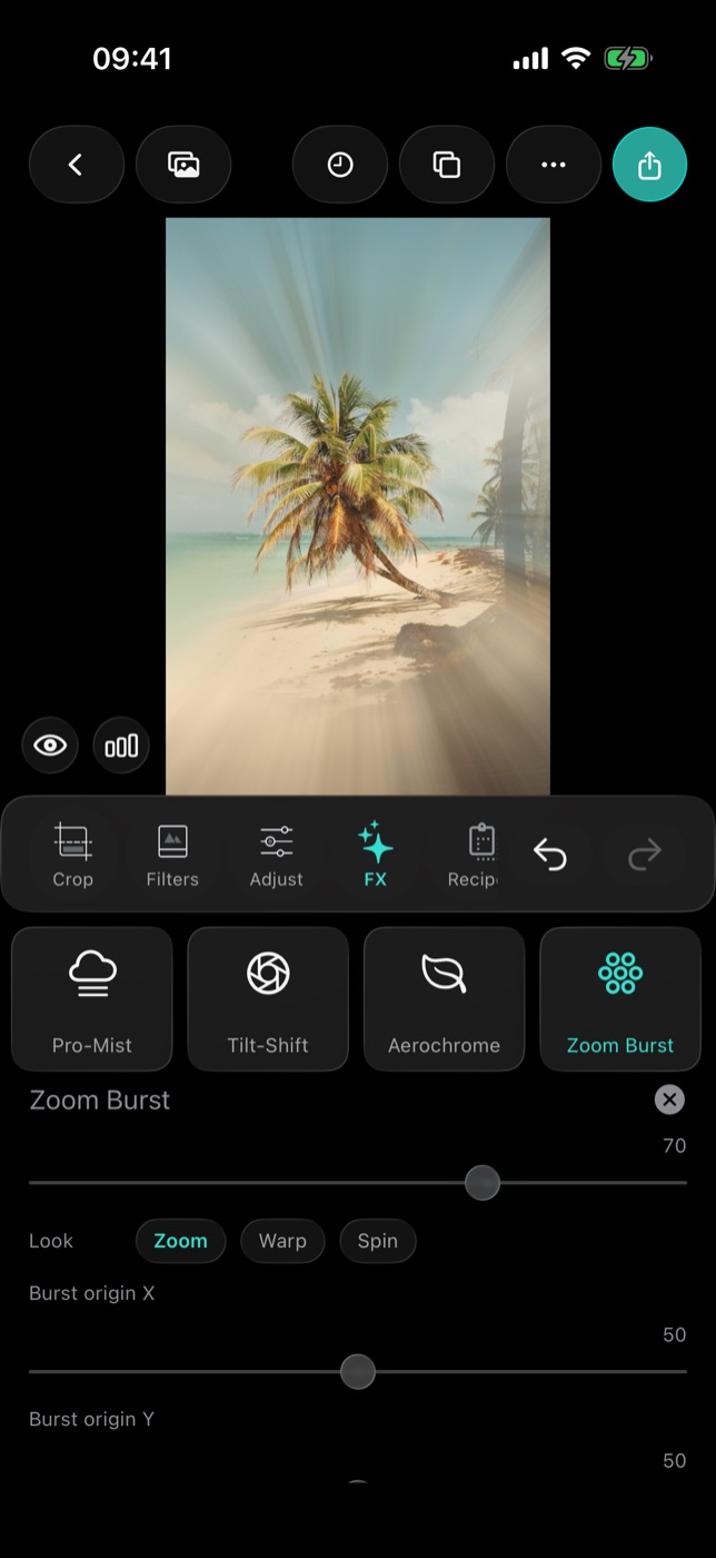 A beach photo with Zoom Burst at 70 and the Zoom look: streaks radiate from the centre while the palm in the middle stays sharp, above the Burst origin X and Burst origin Y sliders.